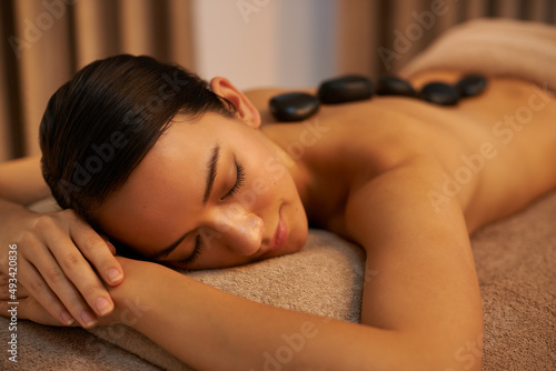 Soothing stones. A young woman enjoying hot stone therapy at the spa.