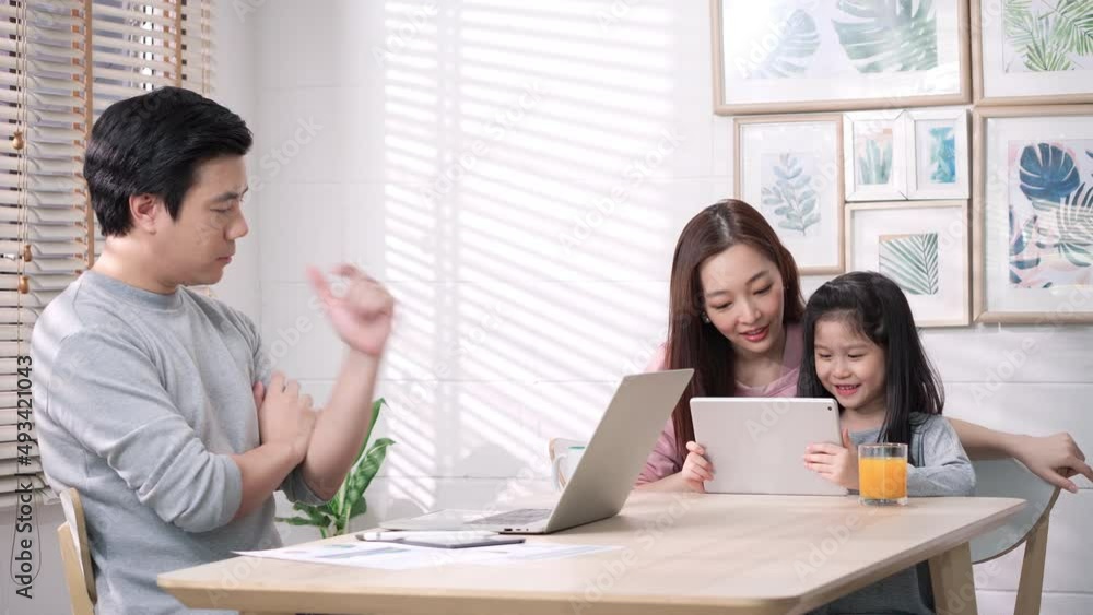 Asian family of businessman working and student girl studying with mom from home. Family happy expression with conference online in internet while being quarantine at home. Stay at home family. Asian family of businessman working and student girl studying with mom from home. Family happy expression with conference online in internet while being quarantine at home. Stay at home family.