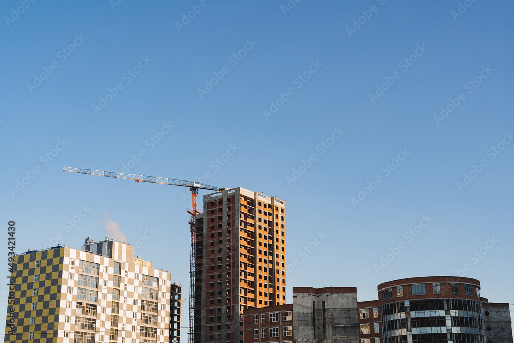 Building a house, a brick house against the sky. Crane is involved in the installation work of the construction of the building