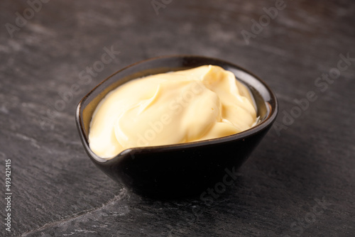 cheese sauce in black bowl on black slate, close up photo