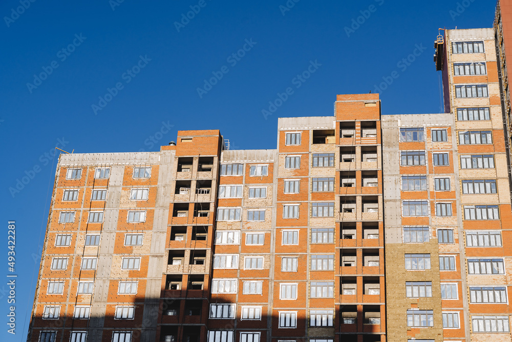 The house is being built against the background of a blue sky. Residential complex of red brick, layout of apartments in the house. Luxury housing.