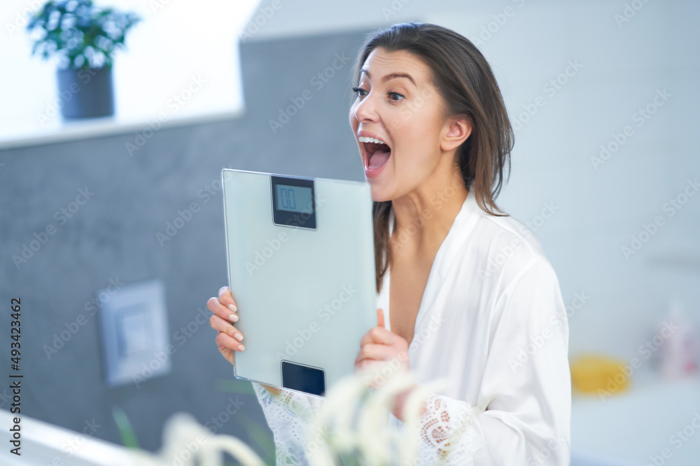Young nice brunette woman in the bathroom with weight scale Young nice brunette woman in the bathroom with weight scale