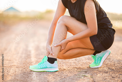 Foto Running woman hugging cramp and calf muscle injury