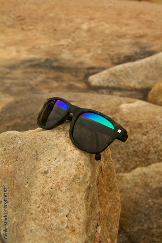 sunglasses with sand resting on a stone