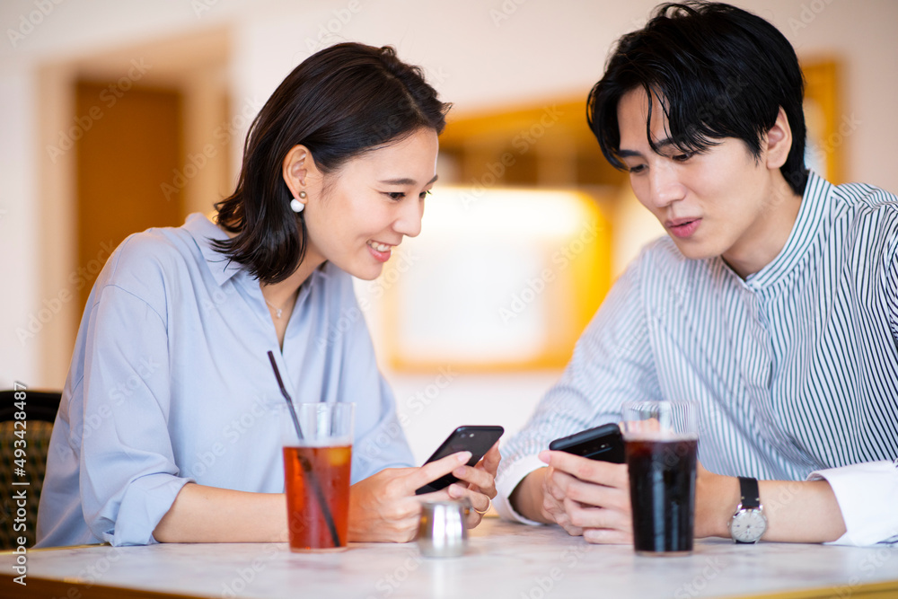 カフェでスマートフォンを見る男女
