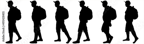 Six tourists with backpacks walk one after another. A group of walking tourists. A woman in a sports cap, a backpack behind her back, shorts. An older woman is hiking. Hiking. Side view, profile.