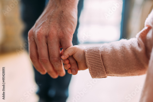 Kleines Mädchen hält die Hand ihres Papas ganz fest in Nahaufnahme horizontal photo