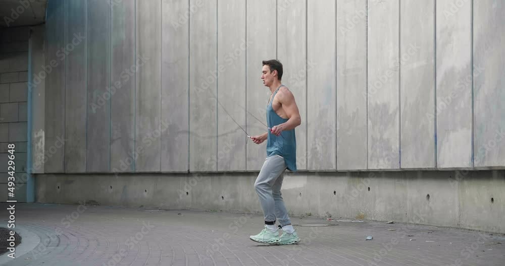 Athletic shirtless man training jump exercise on skipping rope on workout. Sporty man jumping with jumping rope. Young man training cardio exercises Athletic shirtless man training jump exercise on skipping rope on workout. Sporty man jumping with jumping rope. Young man training cardio exercises