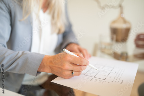 Immobilien Maklerin bei einem Vertragsgespräch mit Grundriss Zeichnung schreibend horizontal