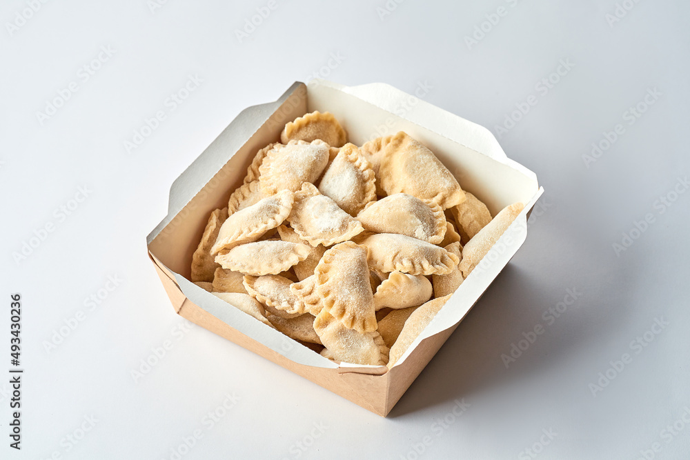 Frozen vareniki with cherries in cardboard on a gray background Frozen vareniki with cherries in cardboard on a gray background