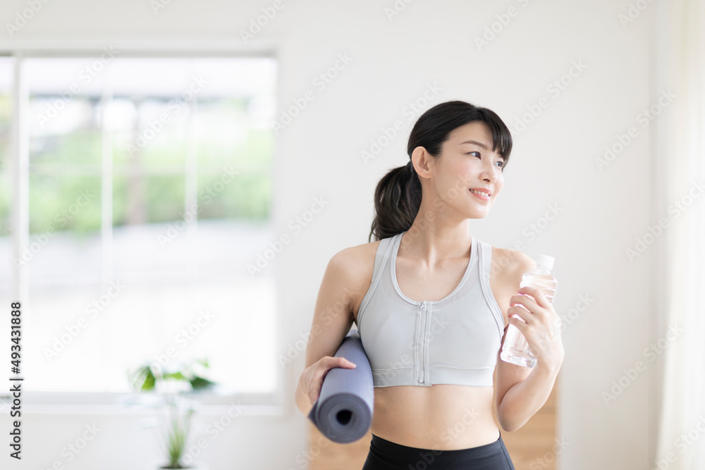 ヨガマットを持って立つ女性 ヨガマットを持って立つ女性