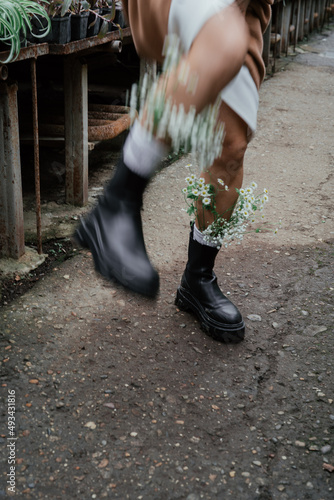 Woman legs in boots with flowers in socks walks in greenhouse photo