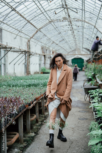 Young attractive asian woman is walking through greenhouse.