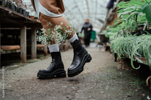 Woman legs in boots with flowers in socks walks in greenhouse photo