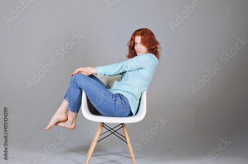 Business portrait of beautiful happy young woman with red curly hair and blue eyes against colorful, gray background. Lifestyle. 