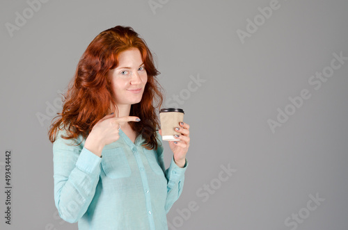 Business portrait of beautiful happy young woman with red curly hair and blue eyes against colorful, gray background. Lifestyle. 