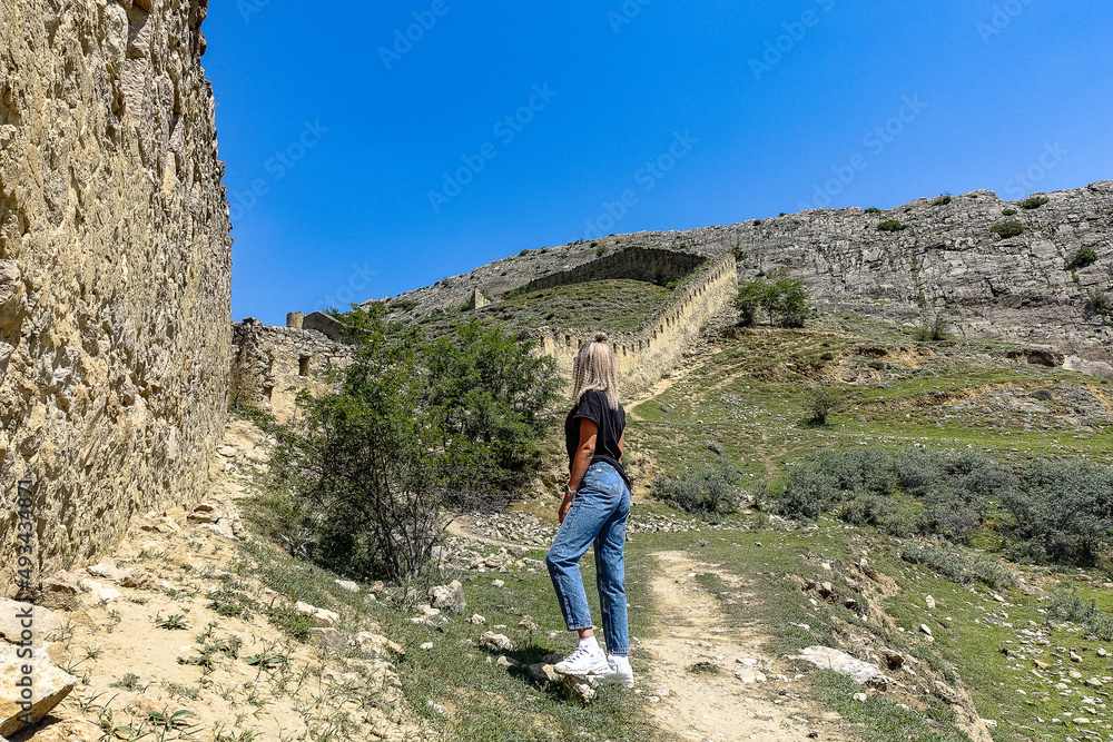 A girl against the background of the Gunib fortress. A protective wall. Russia, Dagestan. June 2021.