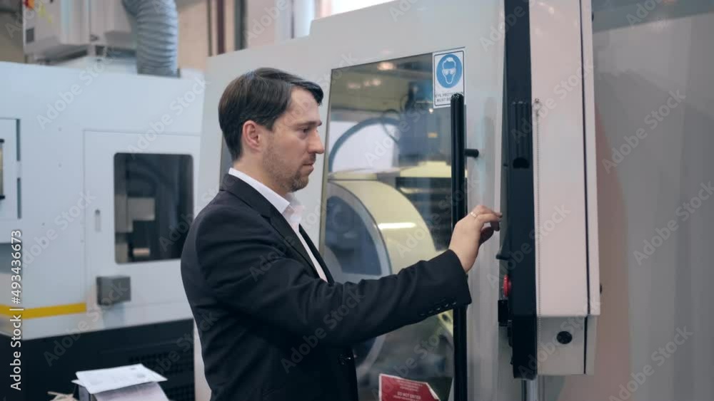 An engineer at an industrial plant. A worker controls the operation of a CNC milling machine. Tablet computer in hand. Drill manufacturing plant. An engineer at an industrial plant. A worker controls the operation of a CNC milling machine. Tablet computer in hand. Drill manufacturing plant.