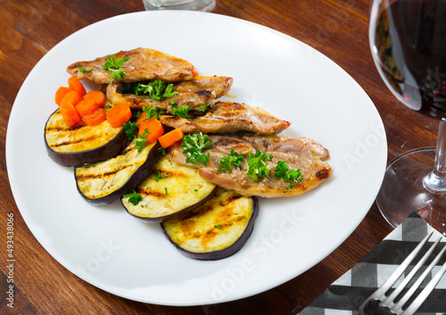 Roasted lamb cutlets served with roasted eggplant slices, carrot and parsley