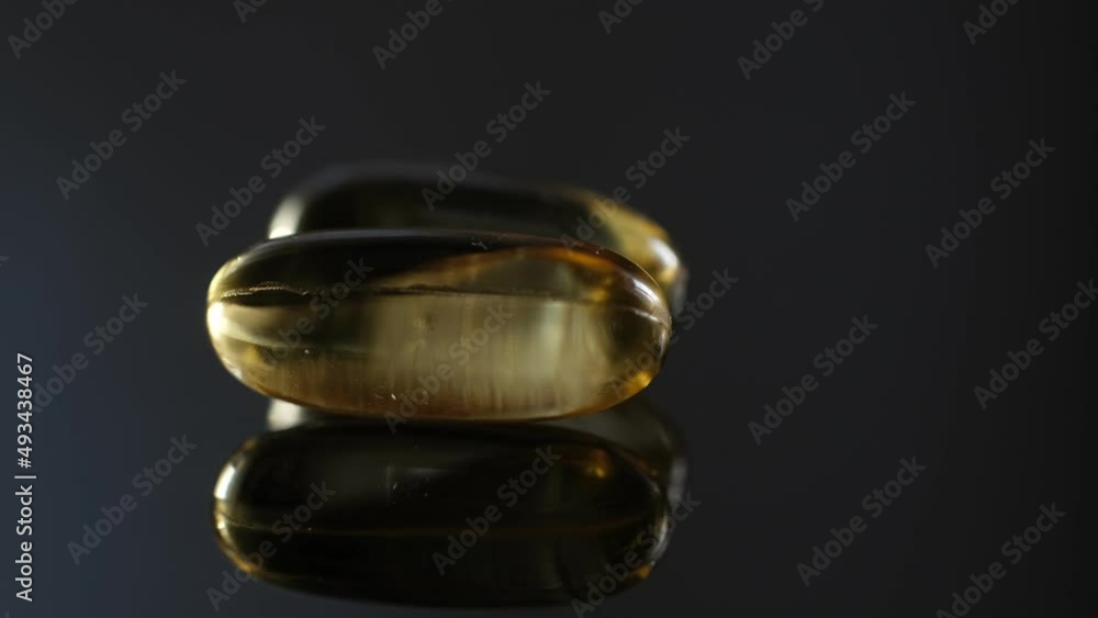 Omega 3 Gold oil capsules on black background, rotation. Close-up of rotating golden pills.Vitamins supplements pills omega 3. Cod liver oil medicines. Fish oil capsules.Omega 3 Fish oil vitamin gel Omega 3 Gold oil capsules on black background, rotation. Close-up of rotating golden pills.Vitamins supplements pills omega 3. Cod liver oil medicines. Fish oil capsules.Omega 3 Fish oil vitamin gel