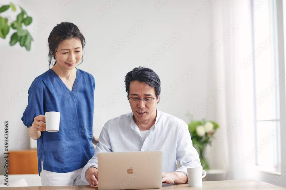 リビングでパソコンを見る夫婦 リビングでパソコンを見る夫婦