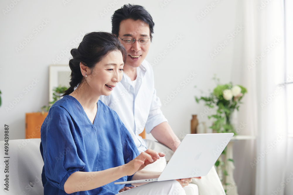 リビングでパソコンを見る夫婦 リビングでパソコンを見る夫婦