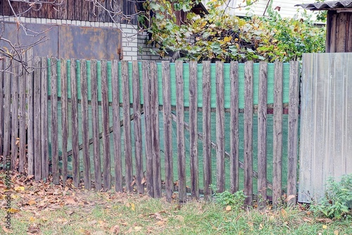Fototapeta Naklejka Na Ścianę i Meble -  closed gray green rural wooden gate and fence made of planks in  grass on the street 