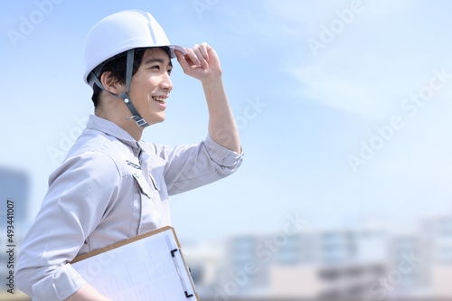Foto メインビジュアルにも！とても使いやすい作業着姿で空を見る男性