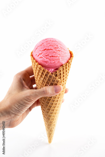 Pink ice cream in a cone in a hand on a white background.