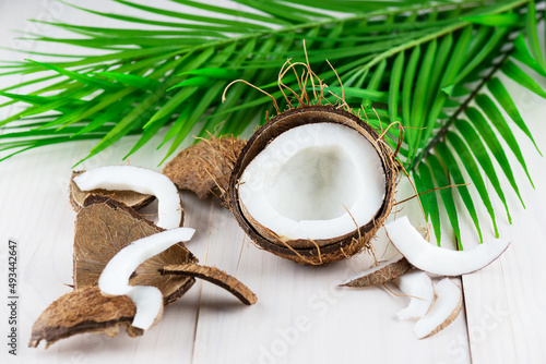 Pieces of coconut with a palm branch on a wooden background.