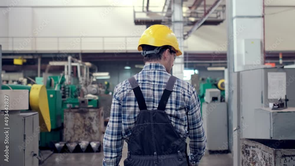 Engineer in Hard Hat is Walking Through Factory. Back View Engineer in Hard Hat is Walking Through Factory. Back View