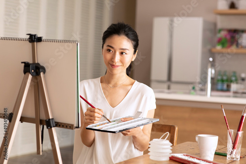 室内で筆を持ち絵を描く女性 photo