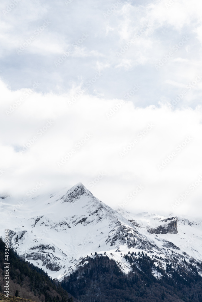Vertical photo of a snow covered mountain with white cloudy sky in french Pyrenees. Inspirational and positive concept. Vertical photo of a snow covered mountain with white cloudy sky in french Pyrenees. Inspirational and positive concept.