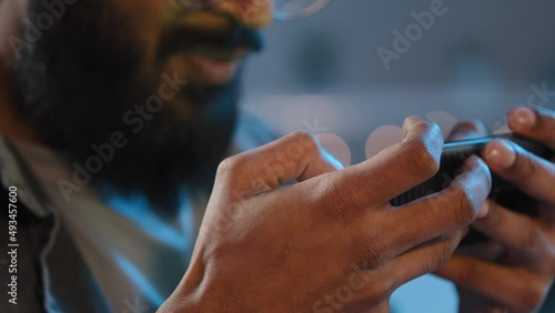 Close aup details male hands unrecognizable bearded man at home in evening night in darkness playing mobile online game play internet sport competition with smartphone winning victory triumph prize photo