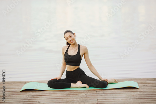 Woman practicing advanced yoga by the water