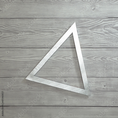 Silver triangle frame on a bright gray wooden background. Text space. Top view. Minimal style. Way  arrow  point.