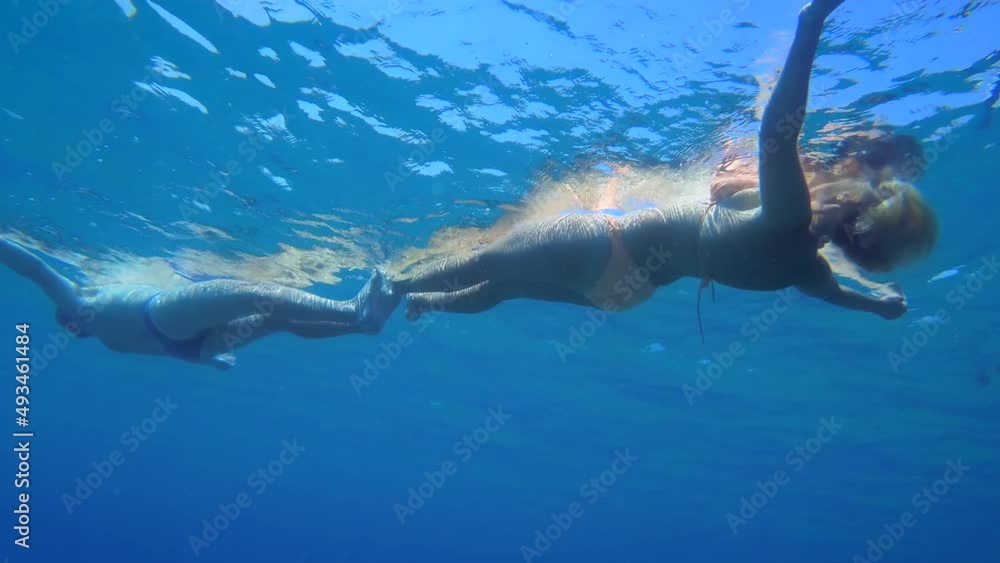 A man and a woman swim on the surface of the sea forming a common figure, the camera slowly lowers down. A man and a woman swim on the surface of the sea forming a common figure, the camera slowly lowers down.
