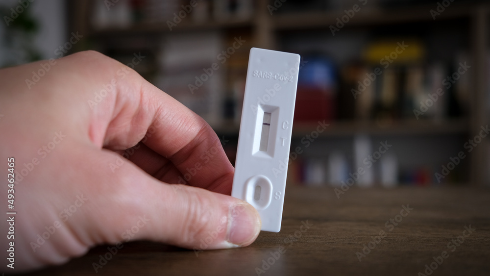 Closeup photo with a hand holding a negative coronavirus test inside a home Closeup photo with a hand holding a negative coronavirus test inside a home