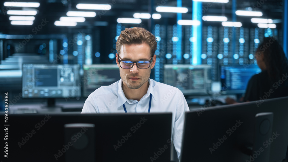Night Office: Young Caucasian Man Working on Two Desktop Computers. Digital Entrepreneur Typing Code, Creating Modern Software, e-Commerce App Design, e-Business Programming Night Office: Young Caucasian Man Working on Two Desktop Computers. Digital Entrepreneur Typing Code, Creating Modern Software, e-Commerce App Design, e-Business Programming