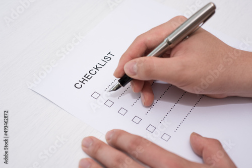 Close-up Of Person's Hand Marking On Checklist Form