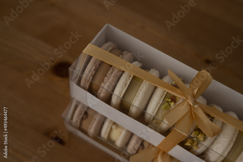 Sweet almond cookies with cream in a box, a composition on a wooden table.