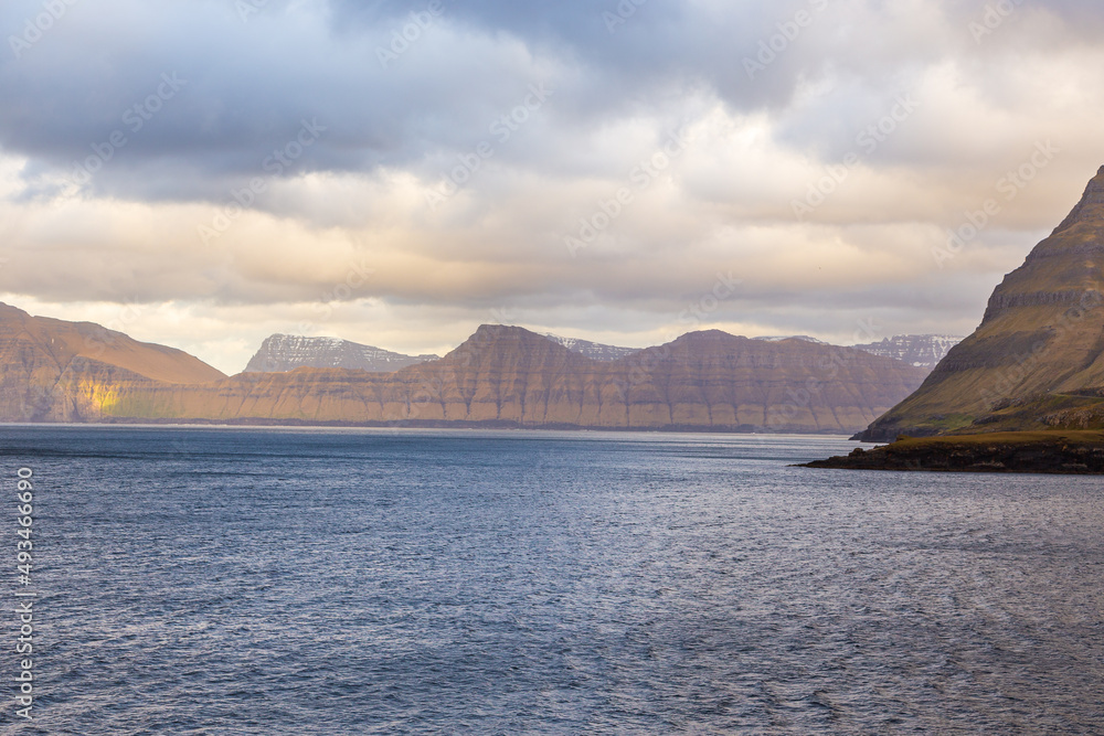 Sunset over the fjord and steep coast in Funnings, Faroe Islands, Denmark.