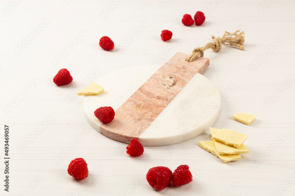 raspberry and round marble on white background