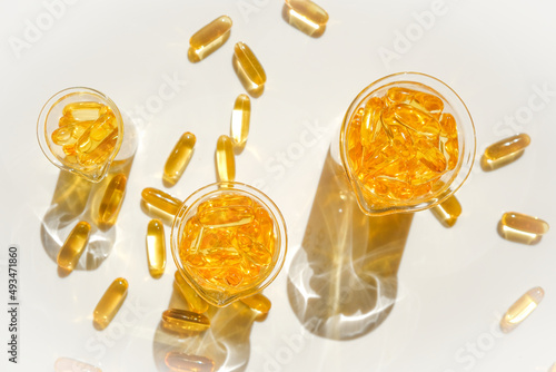 Fish oil gelatin capsules in laboratory transparent flasks on a white background.Healthy eating and food supplements.omega fatty acids. Flying capsules Fish oil.Natural supplements and vitamin