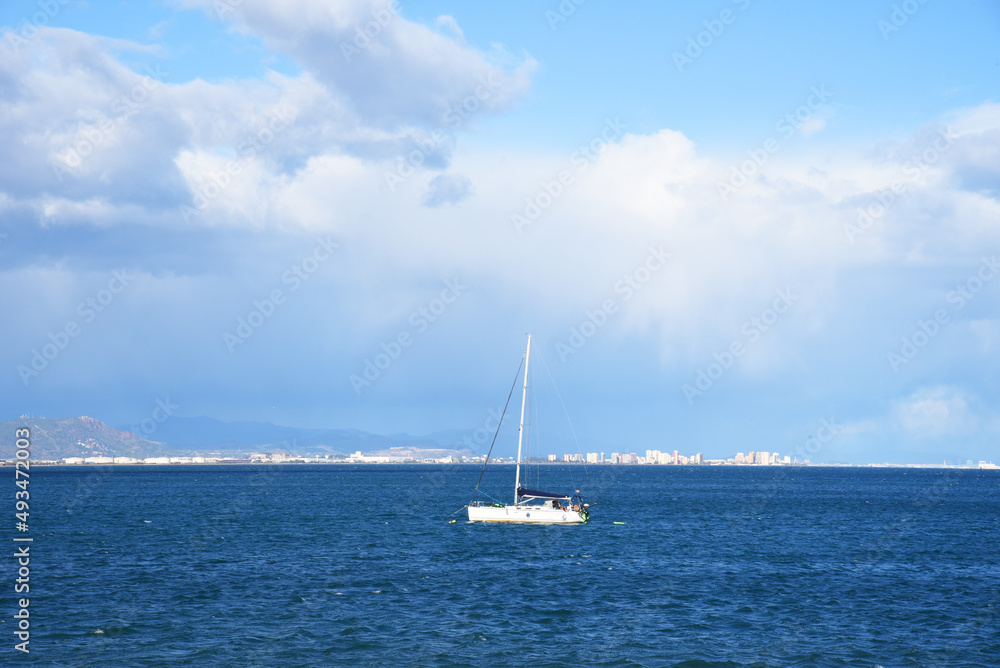 Sailboat at sea on sailing on the waves. Yachtsman during training on a sailboat. Skiff and Sailboat in sea port near the Spanish coast. Sail sport in Yacht club. Sail boat on waves on sunset in sea.