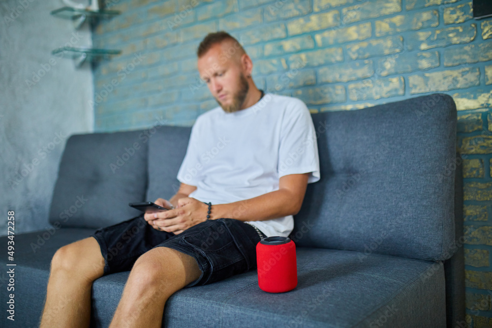 Male testing talking smart wireless speaker, man controlling home devices with a voice commands Male testing talking smart wireless speaker, man controlling home devices with a voice commands