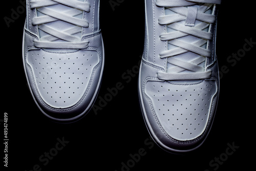 Top view of two white high top sneakers on a black background
