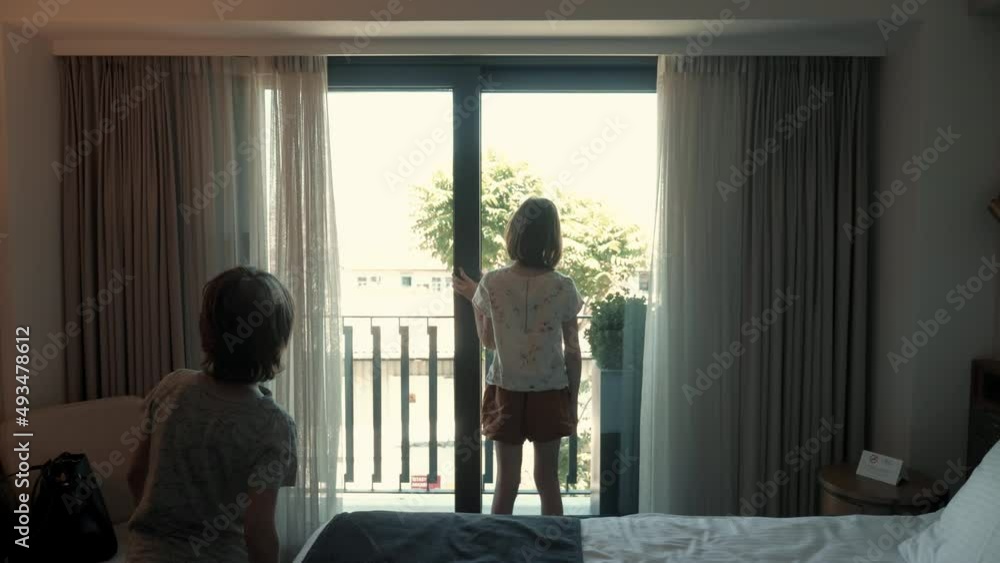 Happy excited teen age girl opens large room window curtains to enjoy beautiful city view, brother boy joins to watch. Happy excited teen age girl opens large room window curtains to enjoy beautiful city view, brother boy joins to watch.