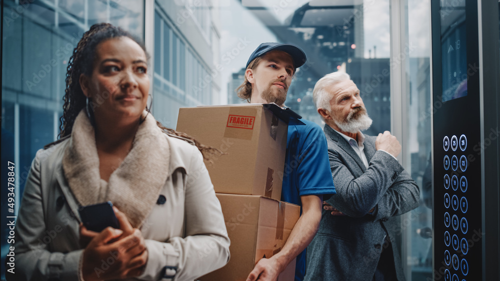 Obraz premium Young Delivery Person Riding Glass Elevator with Businesspeople in Modern Office Building. Mail Courier Holding Cardboard Parcel Boxes. Handsome Mailman Delivering Fragile Packages in Business Center.