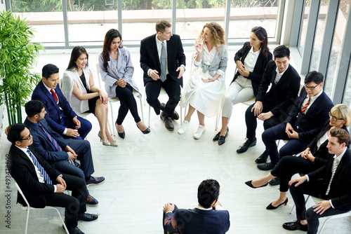 Top view of group of multiethnic busy people working in an office, Aerial view with businessman and businesswoman sitting around a conference room.